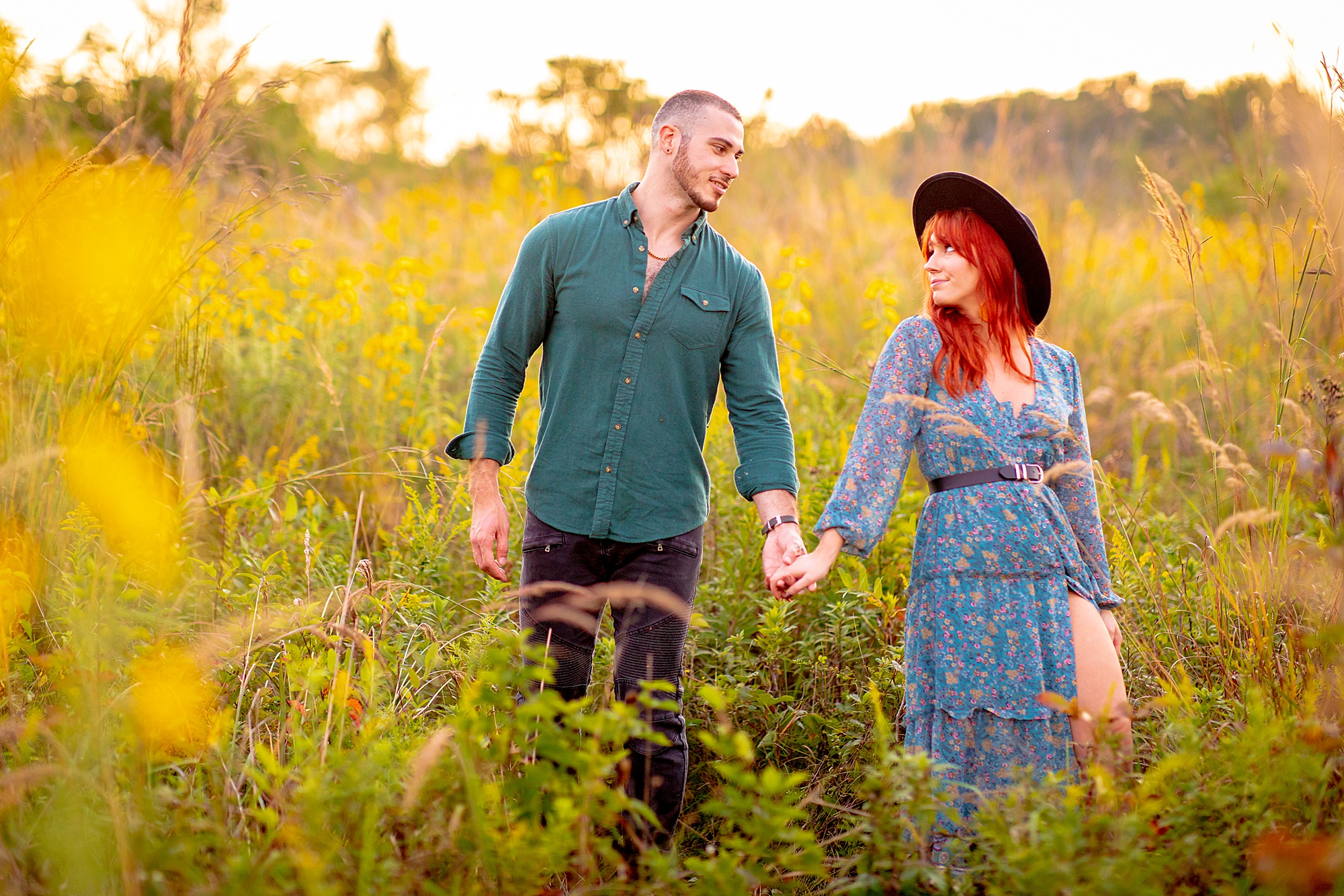 couple holding hands through field 