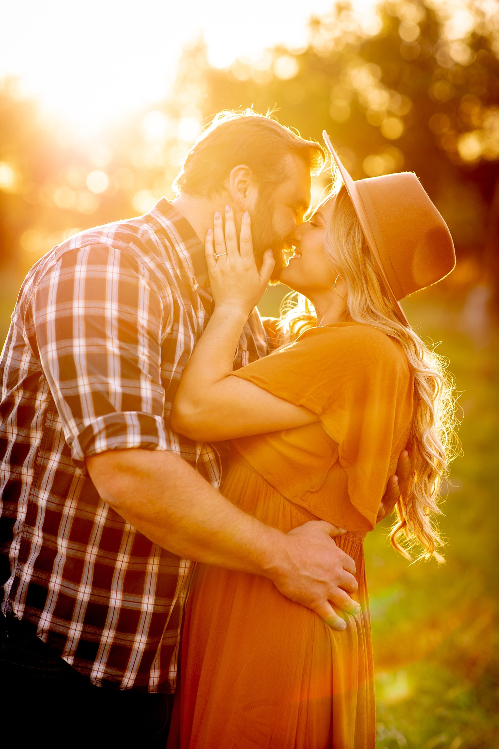 couple kisses with sun glowing around them 